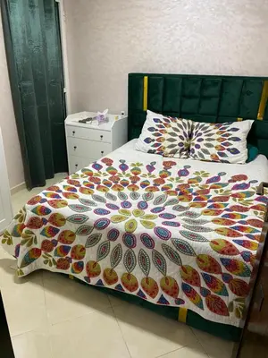a bed with a colorful comforter on top of it at Jnane meknes in Meknès
