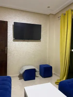 a living room with a flat screen tv and blue stools at Jnane meknes in Meknès