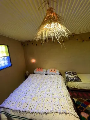 a bedroom with a bed and a chandelier at Gite Amani Guest House in Zaouia Hansala