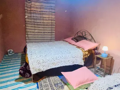 a bedroom with a bed with pink pillows on it at Gite Amani Guest House in Zaouia Hansala