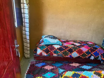 a bed with a colorful blanket and a pillow on it at Gite Amani Guest House in Zaouia Hansala