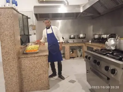a man in a kitchen holding a tray of food at Mahdi gajli in Ouarzazate