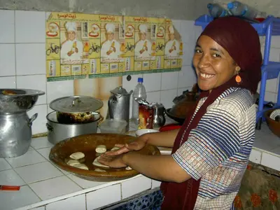 a woman standing in a kitchen preparing food at Mahdi gajli in Ouarzazate