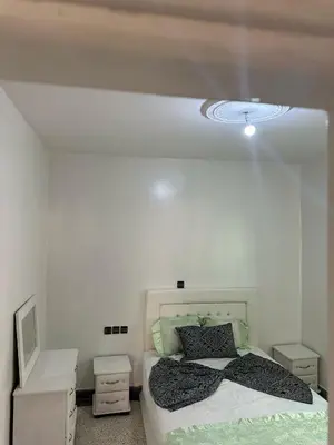 a white bedroom with a bed and a mirror at Appartement Ritage in Meknès