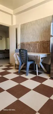 a room with a table and a chair on a checkered floor at Appartement Ritage in Meknès