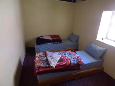 two beds in a small room with a window at gite taghia ahanssal in Taghia