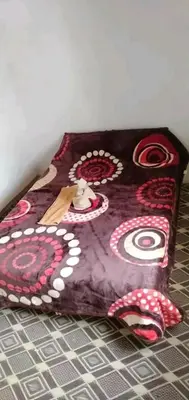 a purple blanket with red flowers on a bed at gite taghia ahanssal in Taghia
