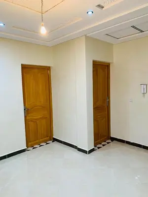 two wooden doors in a room with white walls at Al confort in Fès