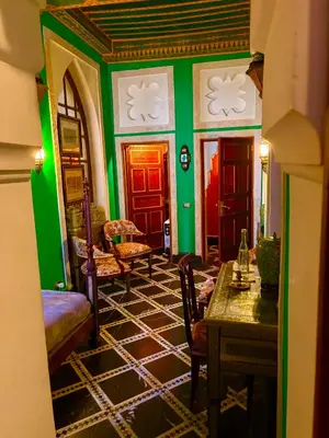 a room with green walls and a table and chairs at Kassr Annoujoum - Luxury Boutique Riad in the Heart of Fès Medina in Fès