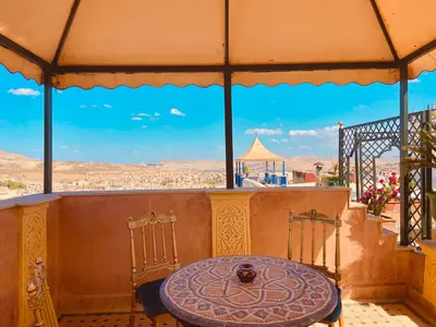 a table and chairs on a balcony with a view at Kassr Annoujoum - Luxury Boutique Riad in the Heart of Fès Medina in Fès
