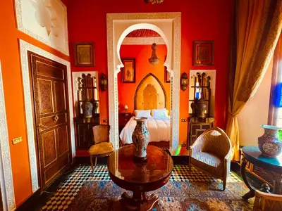 a bedroom with red walls and a bed and a table at Kassr Annoujoum - Luxury Boutique Riad in the Heart of Fès Medina in Fès