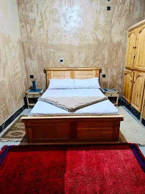 a bedroom with a wooden bed with a red rug at Dar Tissili in Aït Tamellil