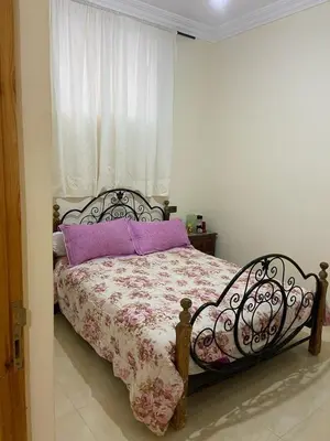 a bedroom with a bed with purple pillows and a window at Yahya in Srarhna