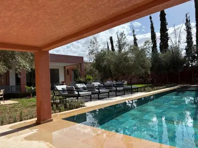 a swimming pool in a yard with chairs and a house at Villa Essalam Marrakech in Marrakech