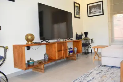a living room with a television on a wooden entertainment center at Villa Essalam Marrakech in Marrakech