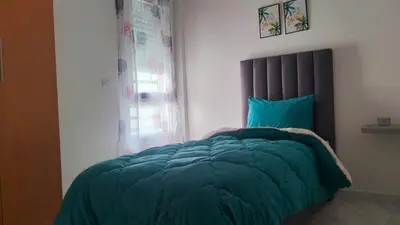 a bedroom with a bed with a green comforter and a window at Rim in Fès