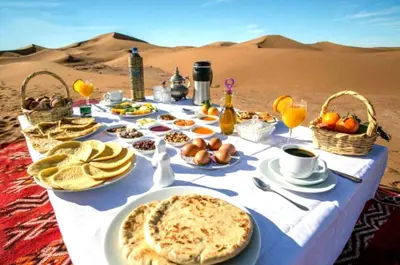 a table in the desert with food and drinks at Merzouga Stars Luxury Camp in Merzouga