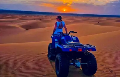 a woman riding a quad bike in the desert at Merzouga Stars Luxury Camp in Merzouga