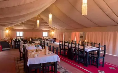 a dining room with tables and chairs in a tent at Merzouga Stars Luxury Camp in Merzouga