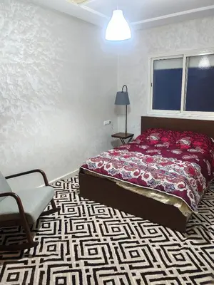 a bedroom with a bed and a chair and a window at Comfortable apartment Meknes in Meknès