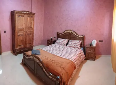 a bedroom with a large bed and a wooden cabinet at Beautiful apartment near airport in Fès