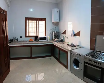 a kitchen with a stove and a sink and a washing machine at Beautiful apartment near airport in Fès