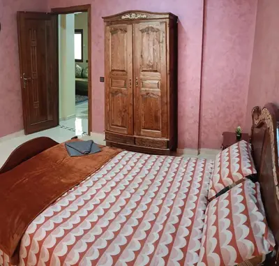 a bed in a room with a wooden cabinet at Beautiful apartment near airport in Fès