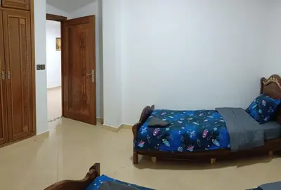 a bedroom with a bed with a blue comforter at Chez Khalid, near airport in Fès