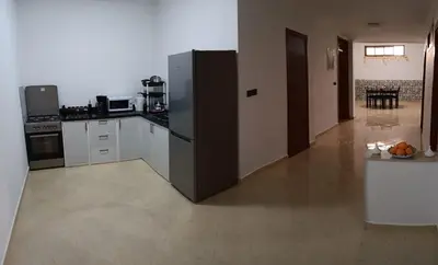 a large kitchen with a refrigerator and a table at Chez Khalid, near airport in Fès