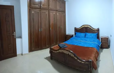 a bedroom with a large wooden bed with blue pillows at Chez Khalid, near airport in Fès
