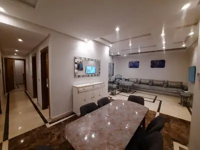 a living room with a table and a couch at Tanger Apt Near Train & Mall in Oulad Akkou