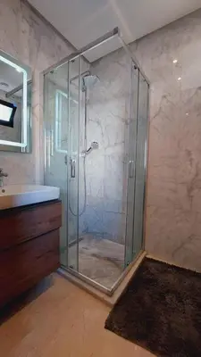 a glass shower in a bathroom with a sink at Tanger Apt Near Train & Mall in Oulad Akkou