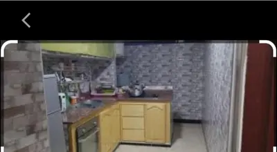 a small kitchen with yellow cabinets and a refrigerator at Maison Zakaria in Zaouiat Cheikh