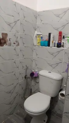 a white toilet in a bathroom with marble walls at Appartement Ghita in Fès
