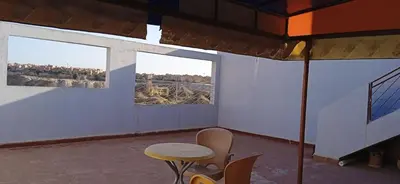 a room with a table and chairs and two windows at Joli appartement de 120 m2 in Meknès