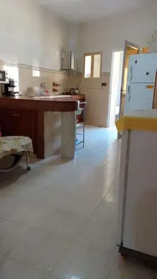 a large kitchen with a table and a refrigerator at Joli appartement de 120 m2 in Meknès