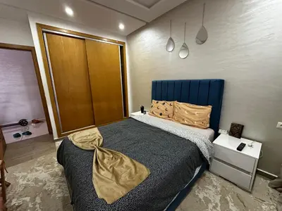 a bedroom with a large bed with a blue headboard at Appartement Familial Spacieux Confort et Tranquillité Assurés in Oulad Akkou