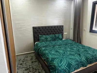 a bedroom with a bed with a green comforter and pillows at Appartement Familial Spacieux Confort et Tranquillité Assurés in Oulad Akkou