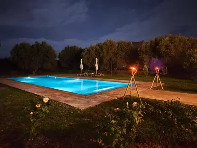 a swimming pool at night with two umbrellas at Domaine du souffle d Amaia in Had Abdallah Rhiat