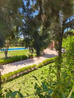 a path in a park with trees and a pool at Domaine du souffle d Amaia in Had Abdallah Rhiat