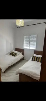 a bedroom with two beds and two windows at Welcome Home in Oulad Hammou