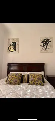 a bed with two pillows and two pictures on the wall at Welcome Home in Oulad Hammou