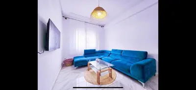 a living room with a blue couch and a table at Welcome Home in Oulad Hammou