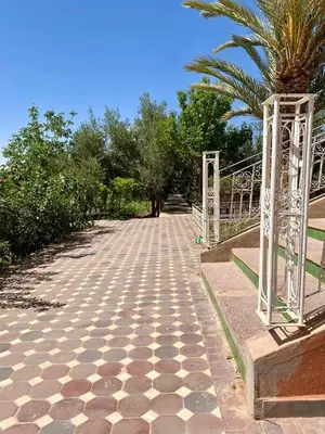 a walkway with a palm tree and a fence at Chez l'habitant tigminnagh in Ouarzazate