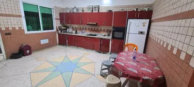 a kitchen with red cabinets and a table and a refrigerator at Chez l'habitant tigminnagh in Ouarzazate
