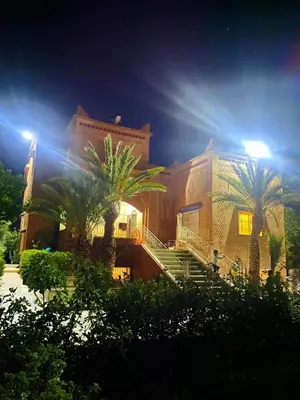 a building with palm trees in front of it at Chez l'habitant tigminnagh in Ouarzazate