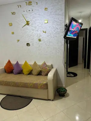 a couch with colorful pillows and a clock on a wall at Bloc A3 AP161 ET4 nakhil lamsala Meknès in Meknès