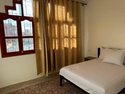 a bedroom with a white bed and two windows at Residence Dallas Warzazate in Ouarzazate