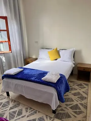 a bedroom with a bed with a blue blanket on it at Residence Dallas Warzazate in Ouarzazate