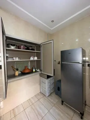 a kitchen with a stainless steel refrigerator and shelves at Appartement neuf meublé pour location journalière in Fès